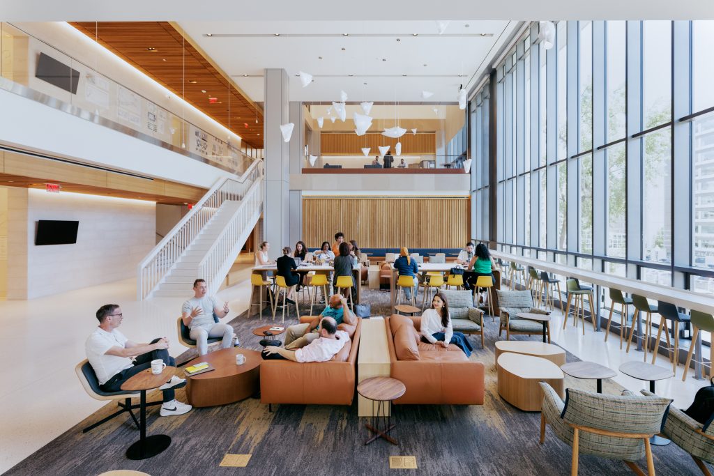 The atrium area of 125 E St. brightly lit with people hanging around.