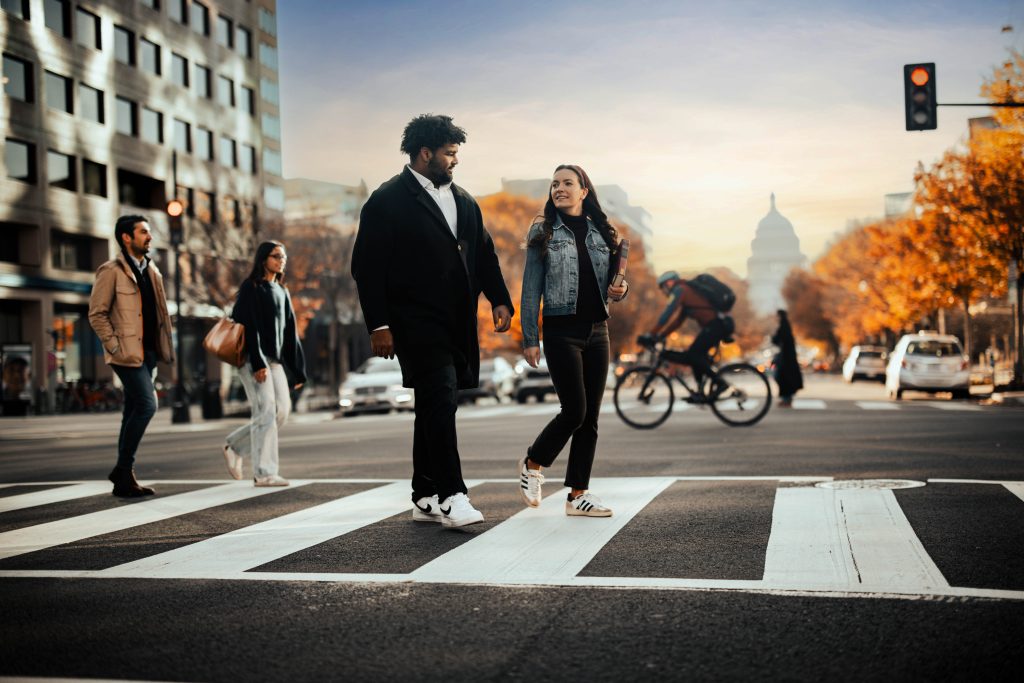 A Black man and white woman walk across the street with the US Capitol in the background