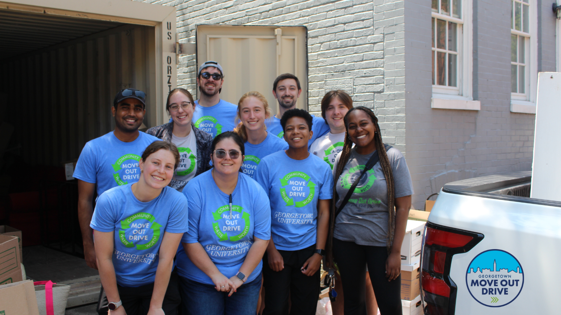 move out drive volunteers in matching blue t shirts pose in front of a storage unit