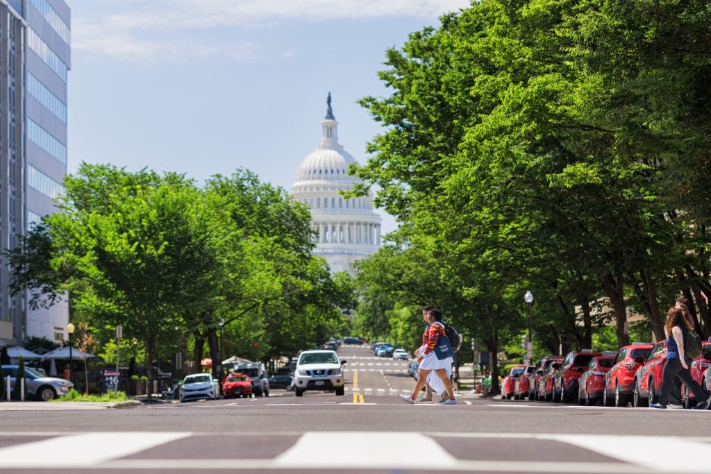 A couple of students cross the street with the US Capitol in the background. Photo by Elman Studio