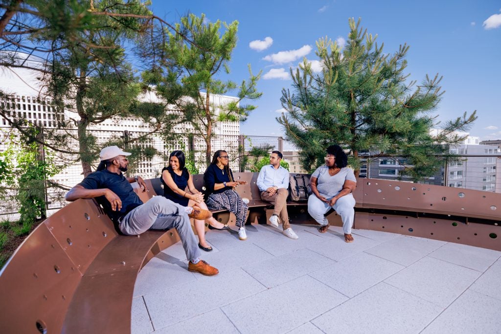 Five students sit on a bench on a terrace that overlooks DC